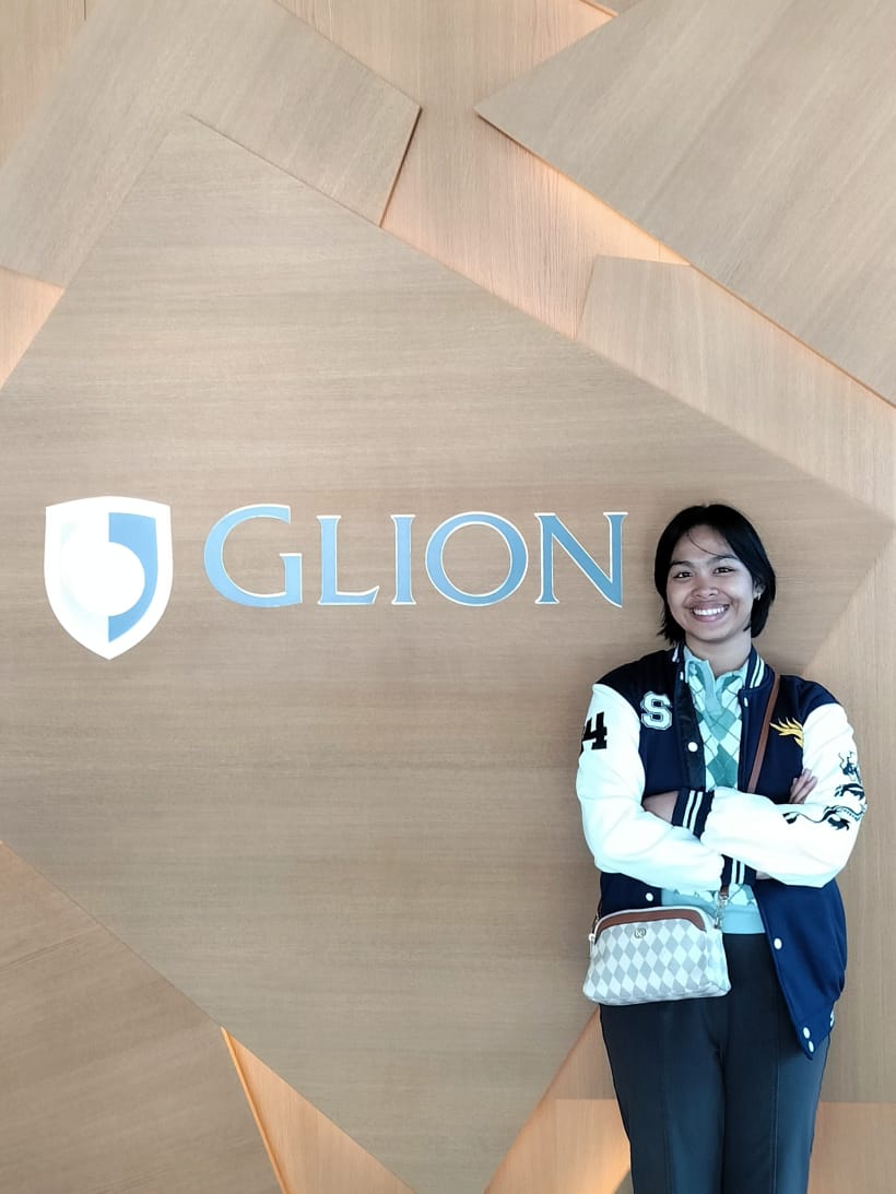 Olivia berdiri di depan identitas kampus Glion di Swiss.