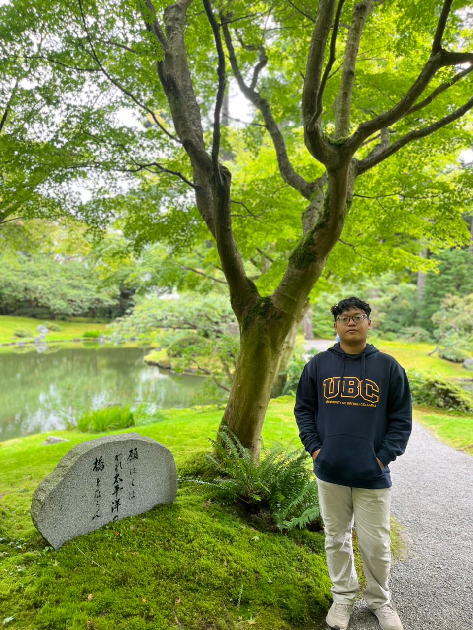 Pasha mengenakan hoodie UBC di taman kampus.
